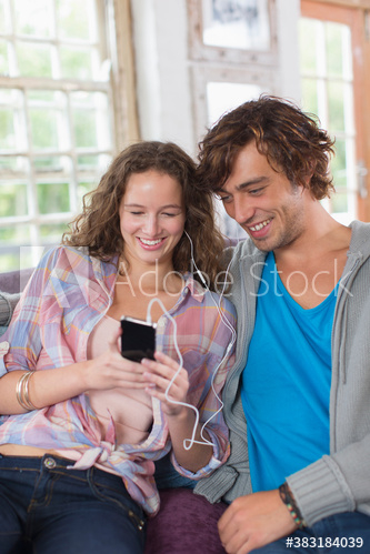 Young couple sharing headphones listening to music Young couple sharing headphones listening to music