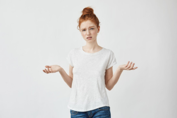 Young displeased redhead woman gesturing confused woman arguing with a boyfriend. white. Free Photo