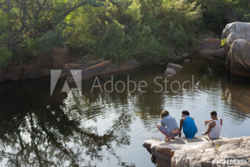 Young friends relaxing on rocks at lakeside Young friends relaxing on rocks at lakeside