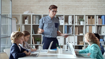 Young male teacher of information technology standing in front of ...