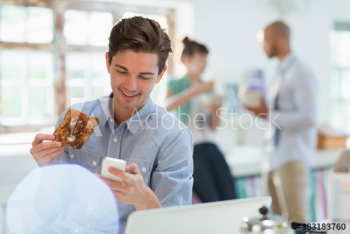 Young man eating toast and checking smart phone in morning kitchen Young man eating toast and checking smart phone in morning kitchen