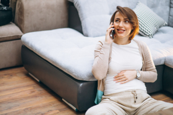 Young pregnant woman at home by the sofa holding tummy Free Photo