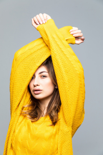 Young pretty woman in yellow sweater with raised hands isolated on gray wall Free Photo