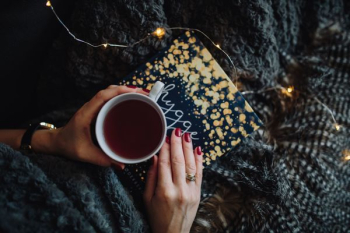Young woman at home reading Hygge book and drinking Young woman at home reading Hygge book and drinking