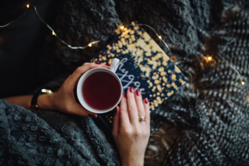 Young woman at home reading Hygge book and drinking Young woman at home reading Hygge book and drinking
