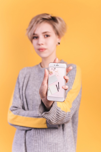 Young woman holding smartphone mockup Free Psd