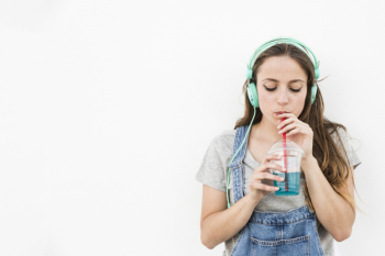Young woman listening music on headphone drinking juice Young woman listening music on headphone drinking juice