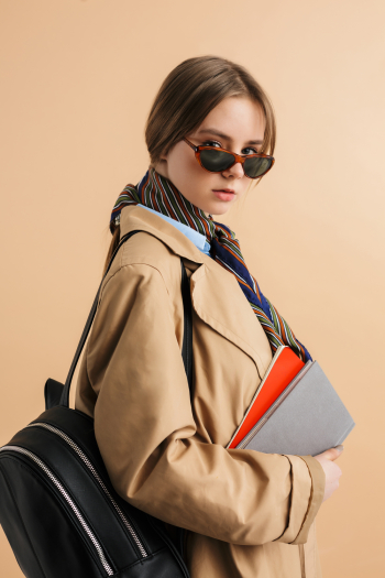 Young woman wearing trench-coat and sunglasses, posing in the city Young woman wearing trench-coat and sunglasses, posing in the city