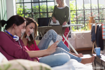 Young women friends reading magazine on sofa Young women friends reading magazine on sofa