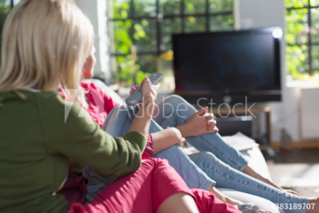 Young women friends watching TV on sofa Young women friends watching TV on sofa
