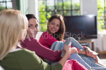 Young women friends watching TV on sofa Young women friends watching TV on sofa
