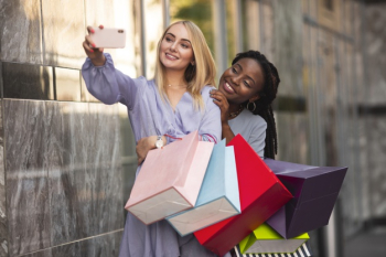 Young women with shopping bags taking selfie Free Photo