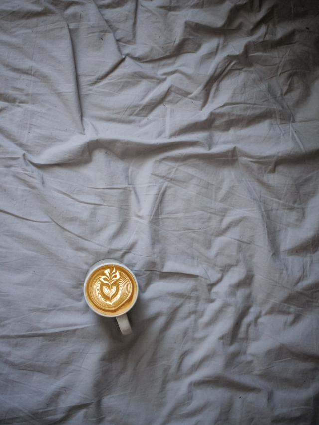 A cup of coffee on a grey bed. Off-centre.