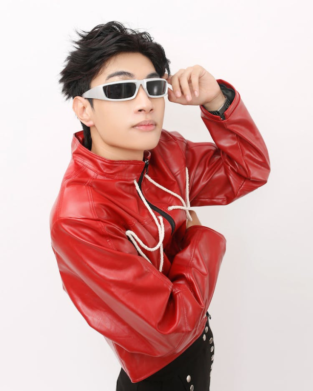 a man in a red leather jacket and sunglasses posing for a picture with his hand on his head and his hand on his head