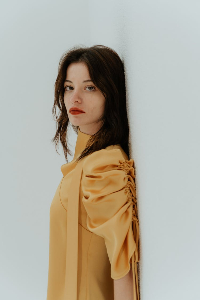 A Woman in a Yellow Top Leaning on a Wall
