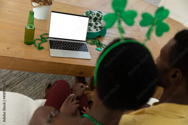 African american couple on st patrick's day video call using laptop with copy space on screen