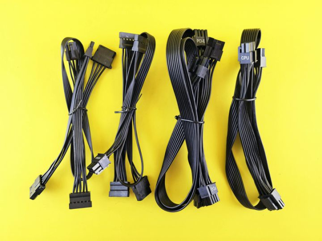 Collection of Black Computer Cables on a Bright Yellow Background