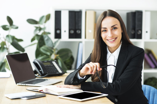 Confident happy young businesswoman sitting at office desk