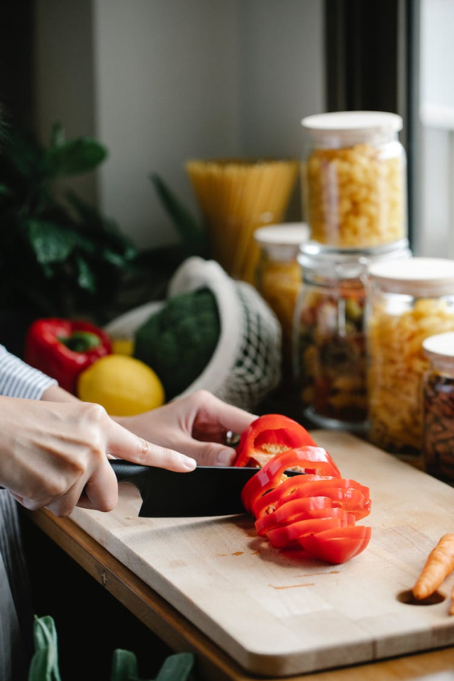 Faceless woman chopping bell pepper during lunch preparation in kitchen