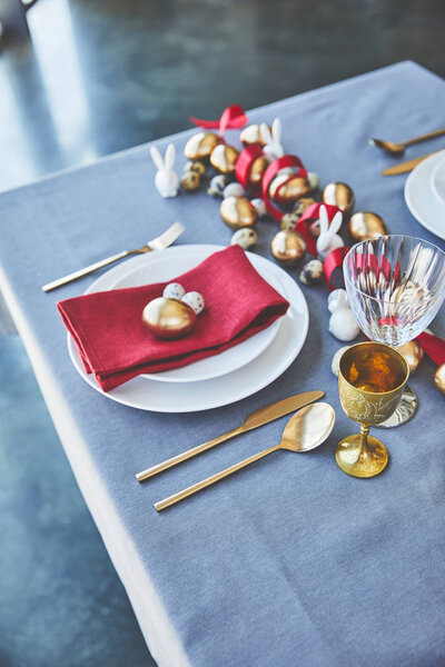 High angle view of easter decorated table with golden eggs and red ribbon