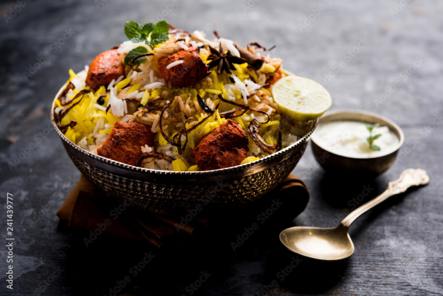 Indian Chicken Tikka Biriyani served in a bowl with yogurt. selective focus