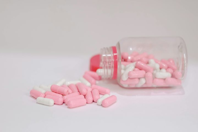 Pink and White Capsules in a Transparent Bottle