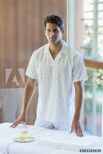 Free: Portrait confident male masseuse standing at spa massage table
