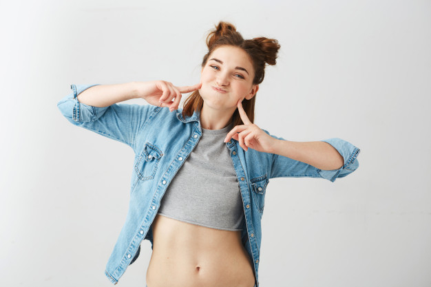 Portrait of funny young pretty girl with two buns making funny face fooling . Free Photo