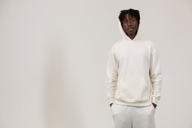Serious young black male in stylish outfit standing in white studio