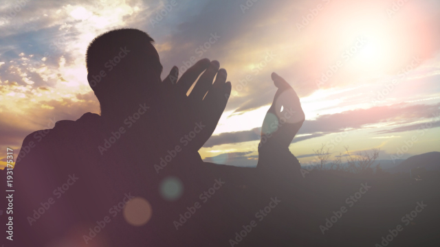 Silhouette of young muslim man praying during sunset