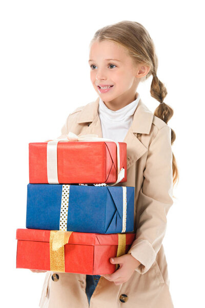 Smiling kid in beige coat holding gifts, isolated on white