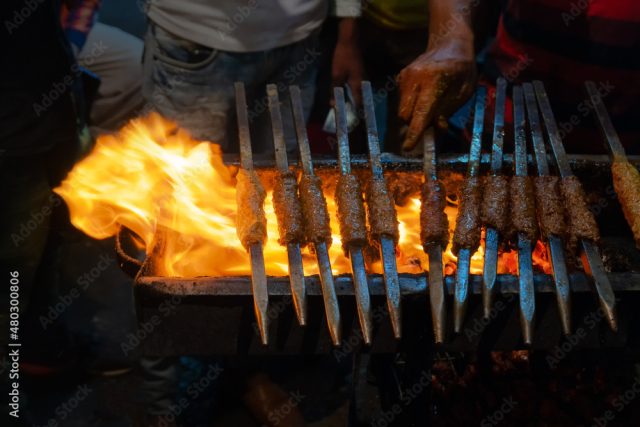 Spicy chicken seekh kababs are being grilled with heat in barbeque with metal skewers,at evening for sale as street food in Old Delhi market. It is famous for spicy Indian non vegetarian street foods.