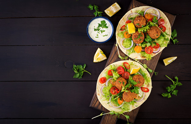 Tortilla wrap with falafel and fresh salad. vegan tacos. vegetarian healthy food. top view Free Photo