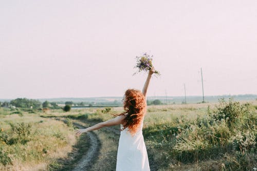 Woman in Dress with a Bouquet of Flowers on the Country Road · Free Stock Photo